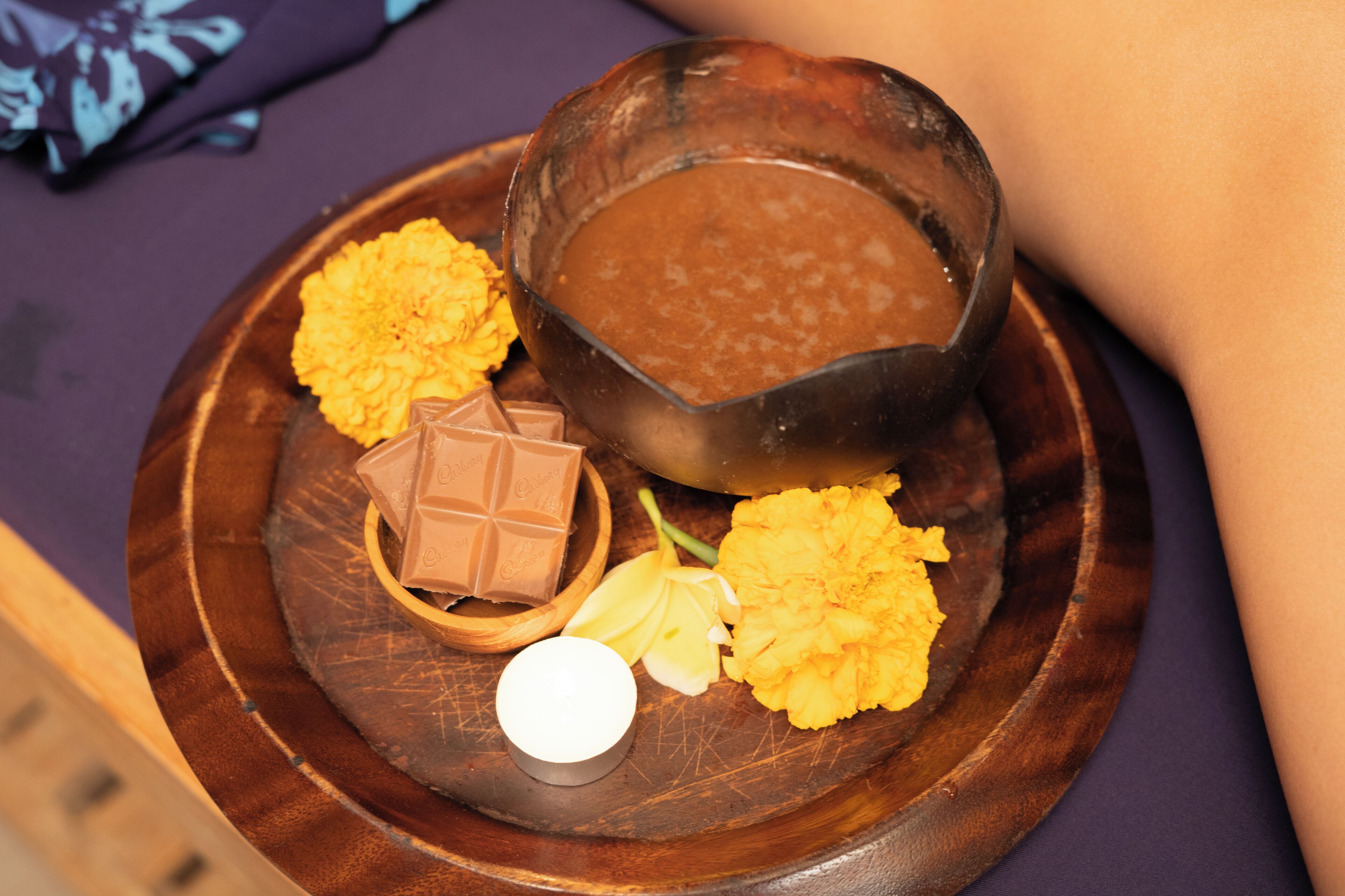 A dessert plate with a chocolate dessert, a small bowl of chocolate, and yellow flowers.