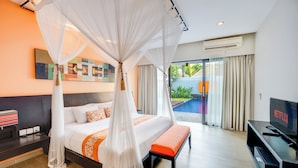 A modern hotel room with a large bed, a TV, and a view of a swimming pool. - Villa Jerami & Spa (Seminyak)