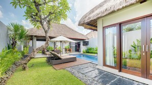 A backyard with a swimming pool, a thatched-roof structure, and outdoor seating. - Villa Jerami & Spa (Seminyak)