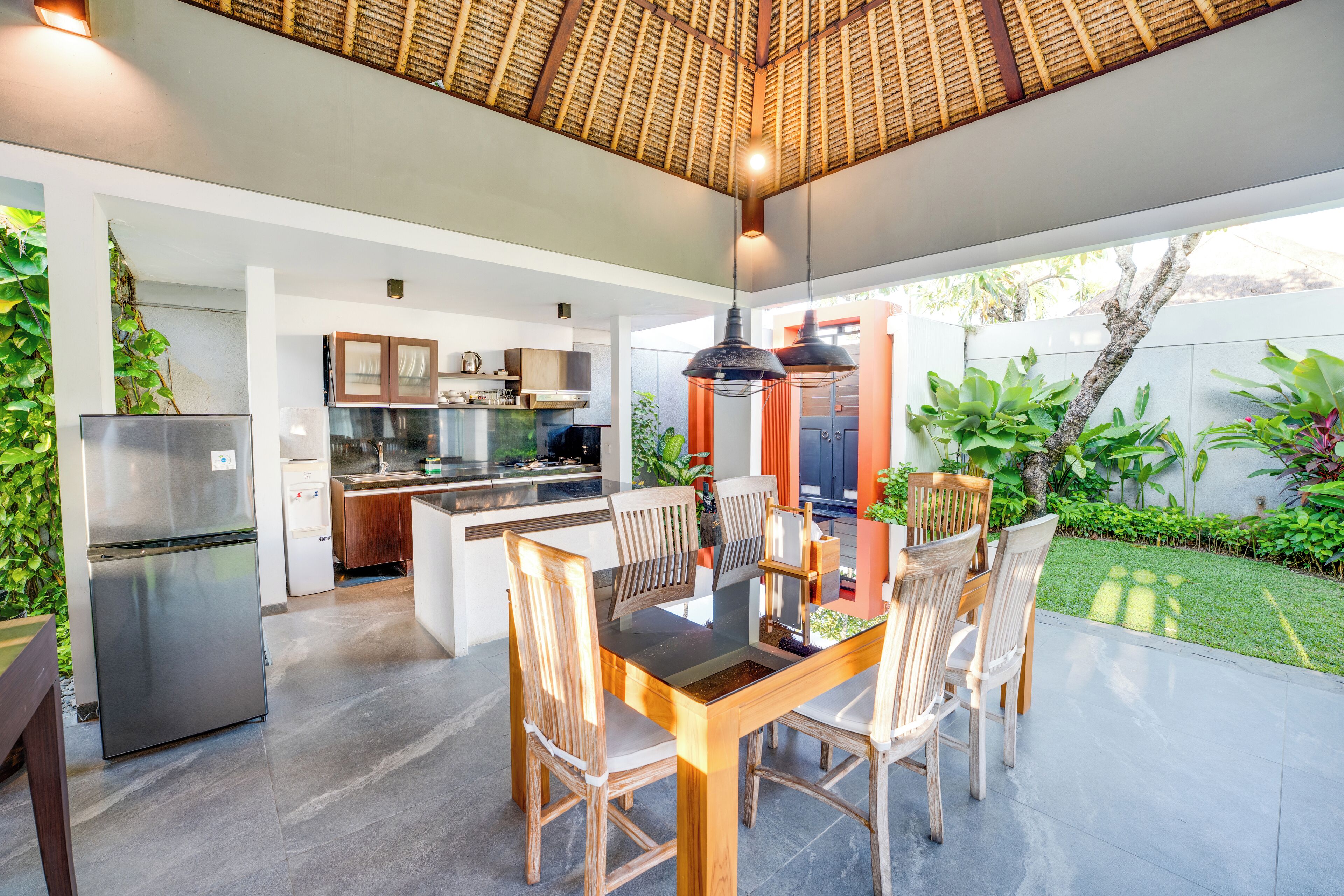 Una cucina moderna con isola centrale, elettrodomestici in acciaio inossidabile e zona pranzo con sedie in legno e tavolo in vetro.