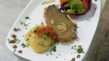 A plate with a meat dish, a side of boiled potatoes, and a mixed vegetable salad.