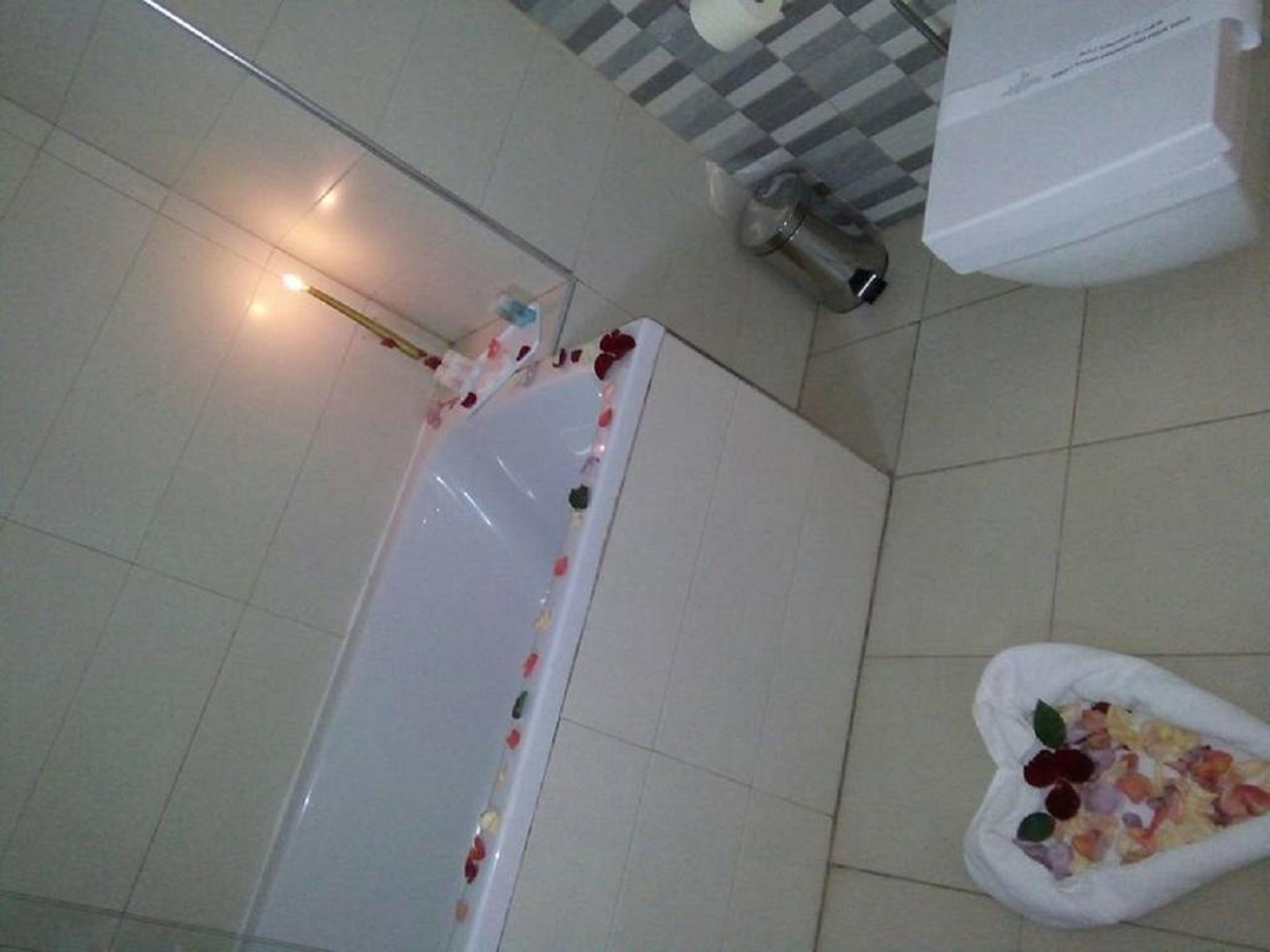 Ein Badezimmer mit einer Badewanne, einer Dusche und einem weißen Mülleimer.