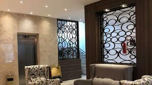 A modern lobby with a sofa, armchairs, a coffee table, and a decorative wall.