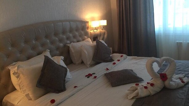 A hotel room with a large bed, a tufted headboard, and a wall-mounted lamp. - Rym el Djamil Hotel (Annaba)