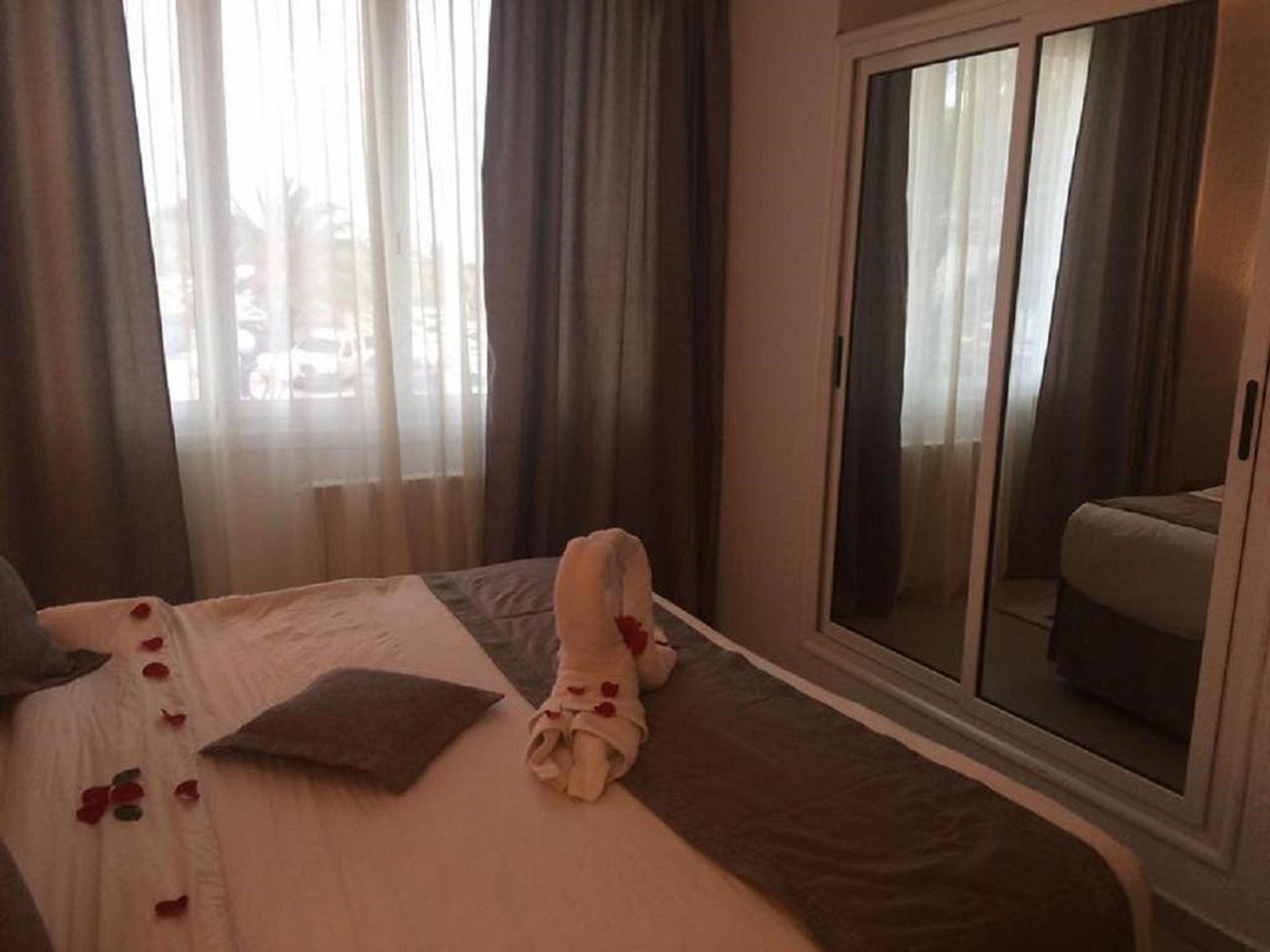 Una camera d'albergo con un letto, un'ampia finestra con tende, una porta scorrevole e vista sull'esterno.