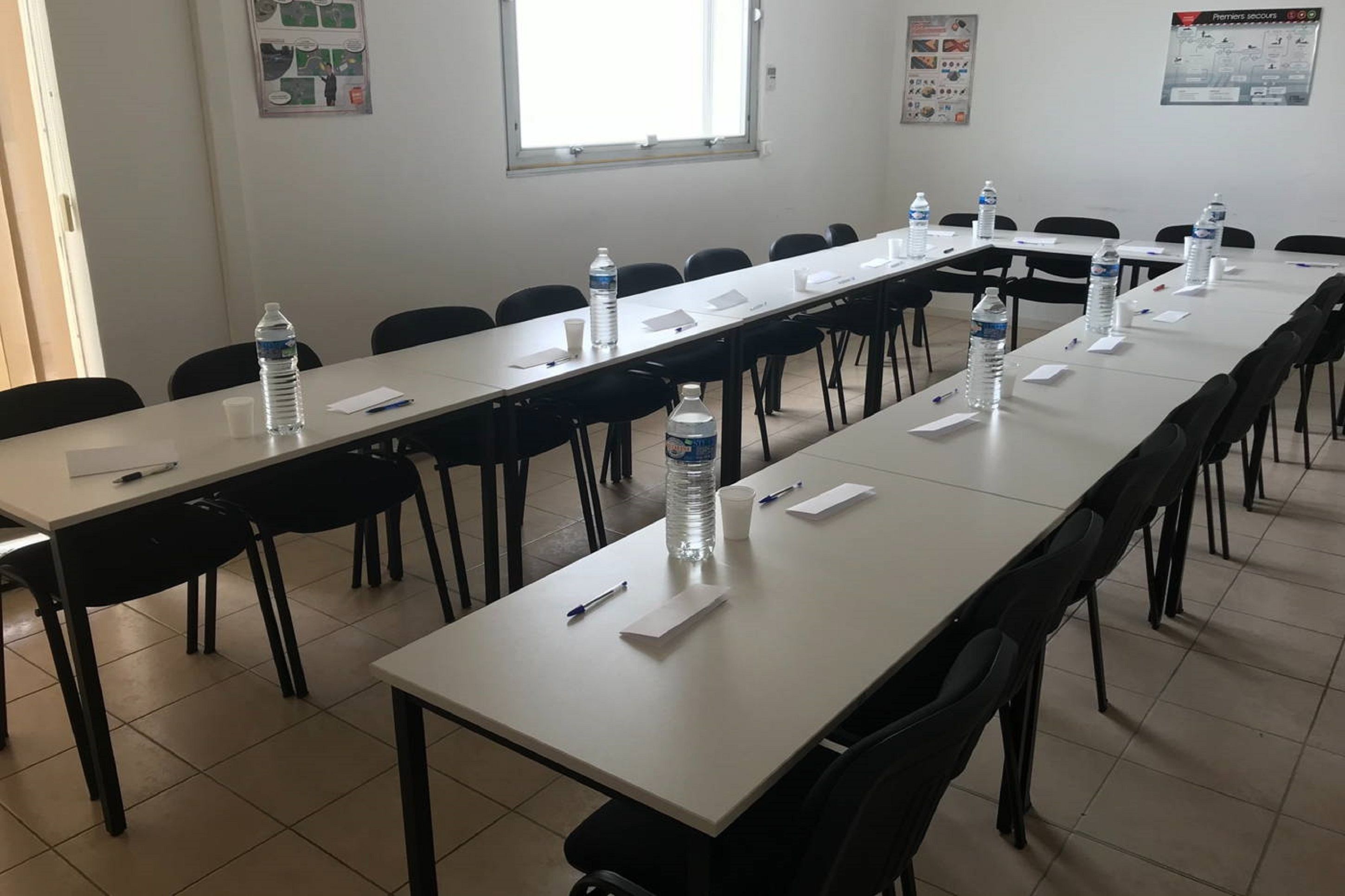A conference room with long tables, chairs, water bottles, and papers.