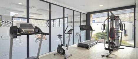 Un gimnasio moderno con cintas de correr, elípticas y una máquina de pesas.