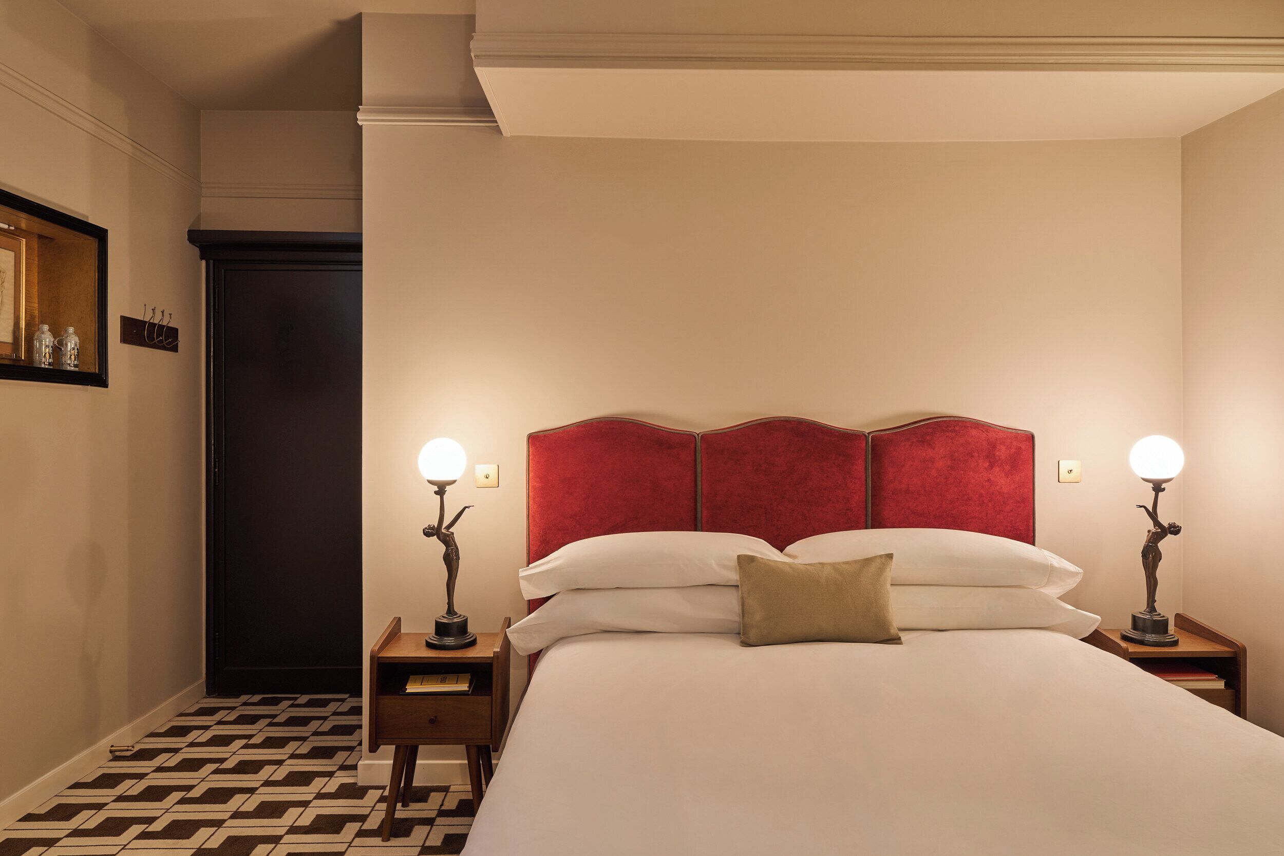 Ein Hotelzimmer mit einem großen Bett, zwei Nachttischen, einem roten Kopfteil und zwei Wandlampen.