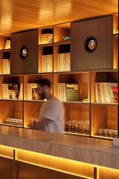 Una zona de bar con estantes de madera que incluyen libros y discos de vinilo.