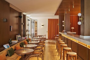 A modern bar area with wooden furniture, a counter, and a seating area with round tables and chairs. - Le Berger Latroupe Hotel (Brussels)