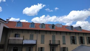 A row of buildings with multiple windows and balconies, under a clear blue sky with scattered clouds. - Chez Brigitte Guesthouse (Nice)