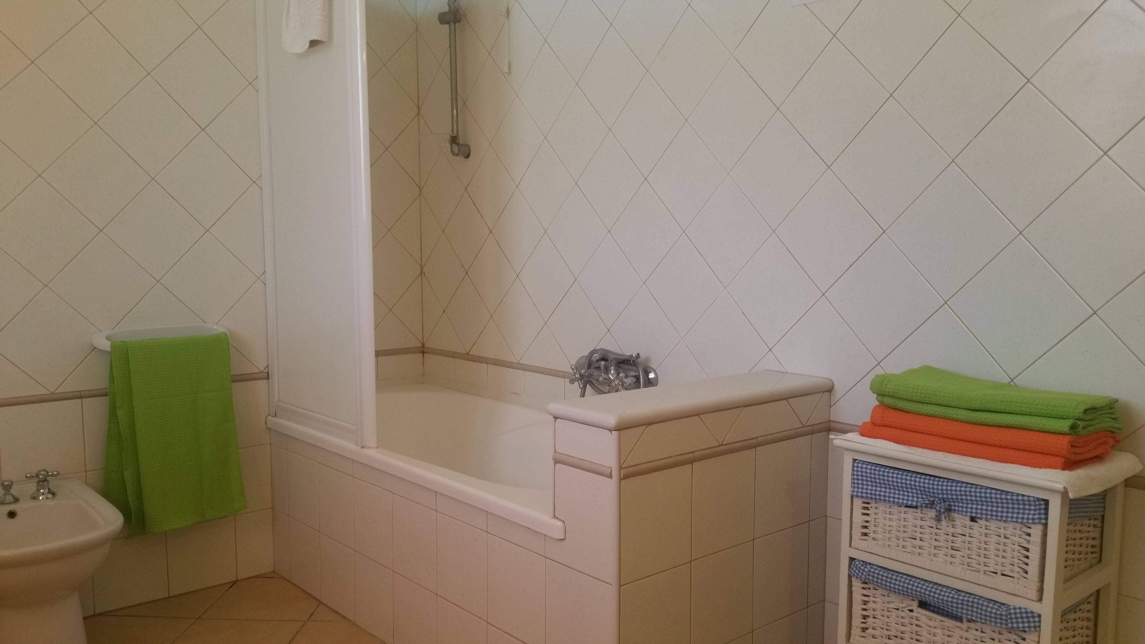 Et badeværelse med badekar, vask og en stak foldede håndklæder.