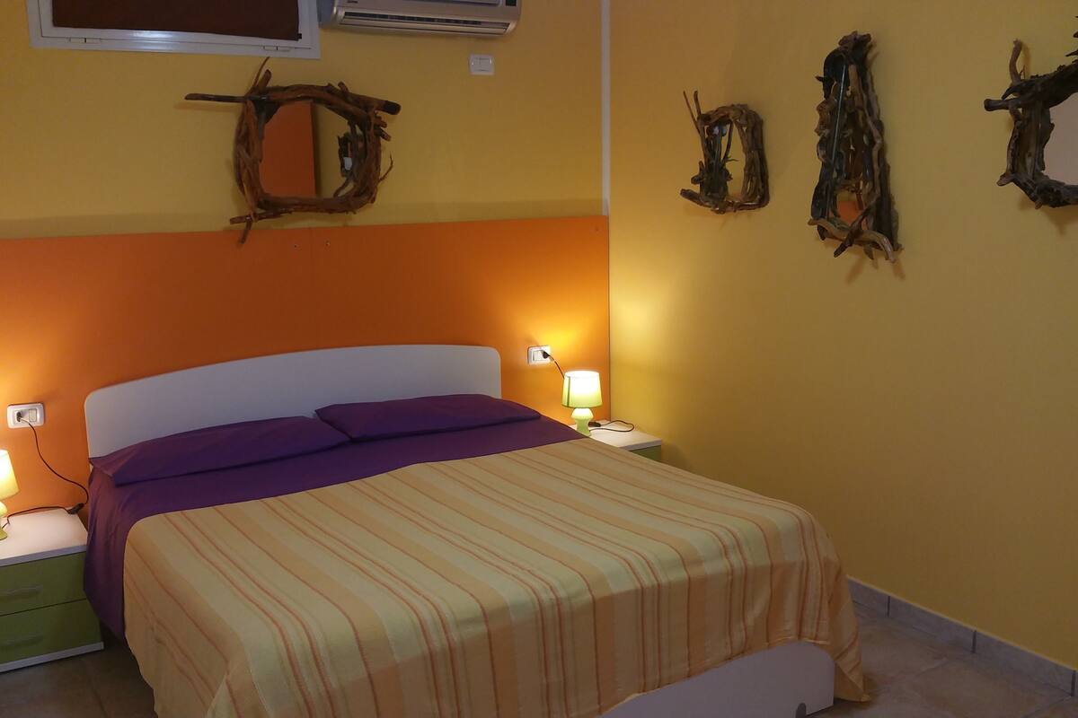Ein Schlafzimmer mit einem Bett, zwei Nachttischen mit Lampen und Wanddekoration.