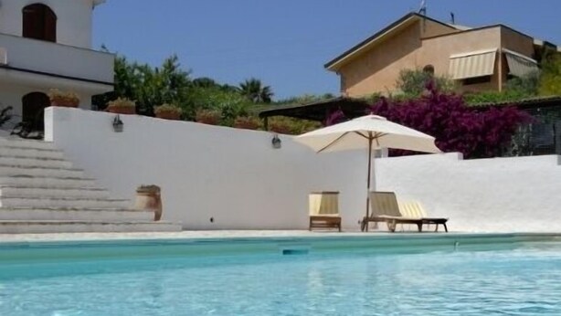 A swimming pool with clear water, surrounded by white walls and a few lounge chairs. - Il Sogno di Alghero (Alghero)