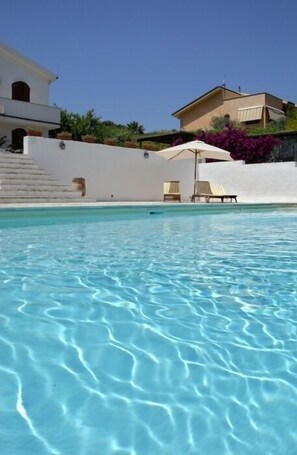 A swimming pool with clear water, surrounded by white walls and a few lounge chairs. - Il Sogno di Alghero (Alghero)