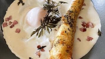 Un plat composé d’un œuf poché, de poisson et d’une sauce crémeuse, le tout garni d’herbes aromatiques.
