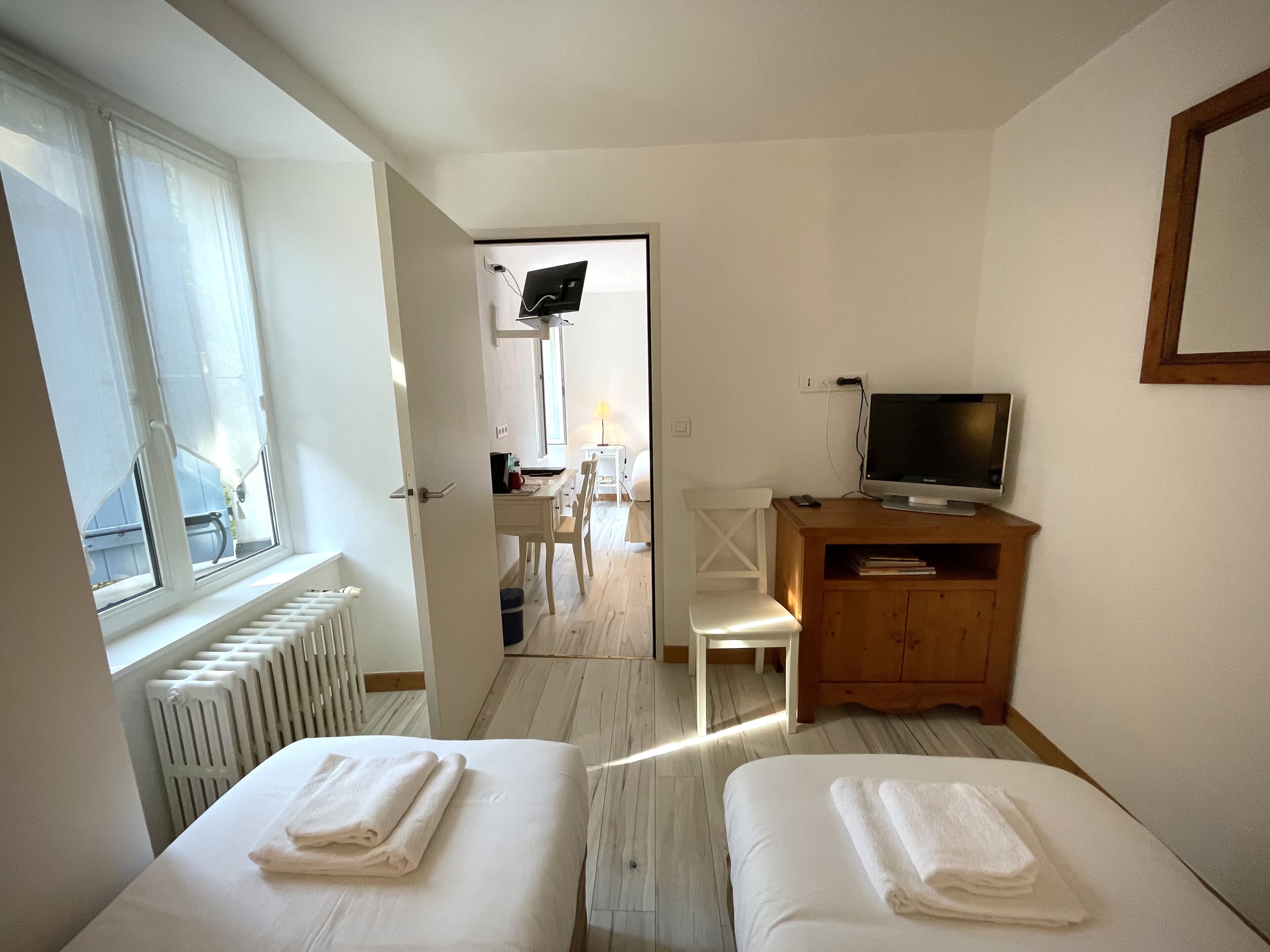 A hotel room with two beds, a TV, a wooden cabinet, and a desk with a chair.