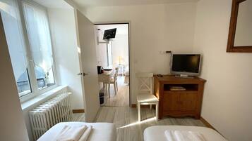 A hotel room with two beds, a TV, a wooden cabinet, and a desk with a chair.