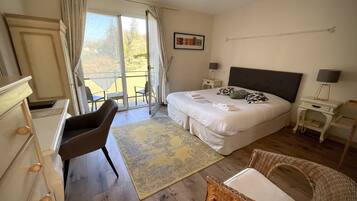 A bedroom with a large bed, a chair, a small table, and a balcony with chairs.