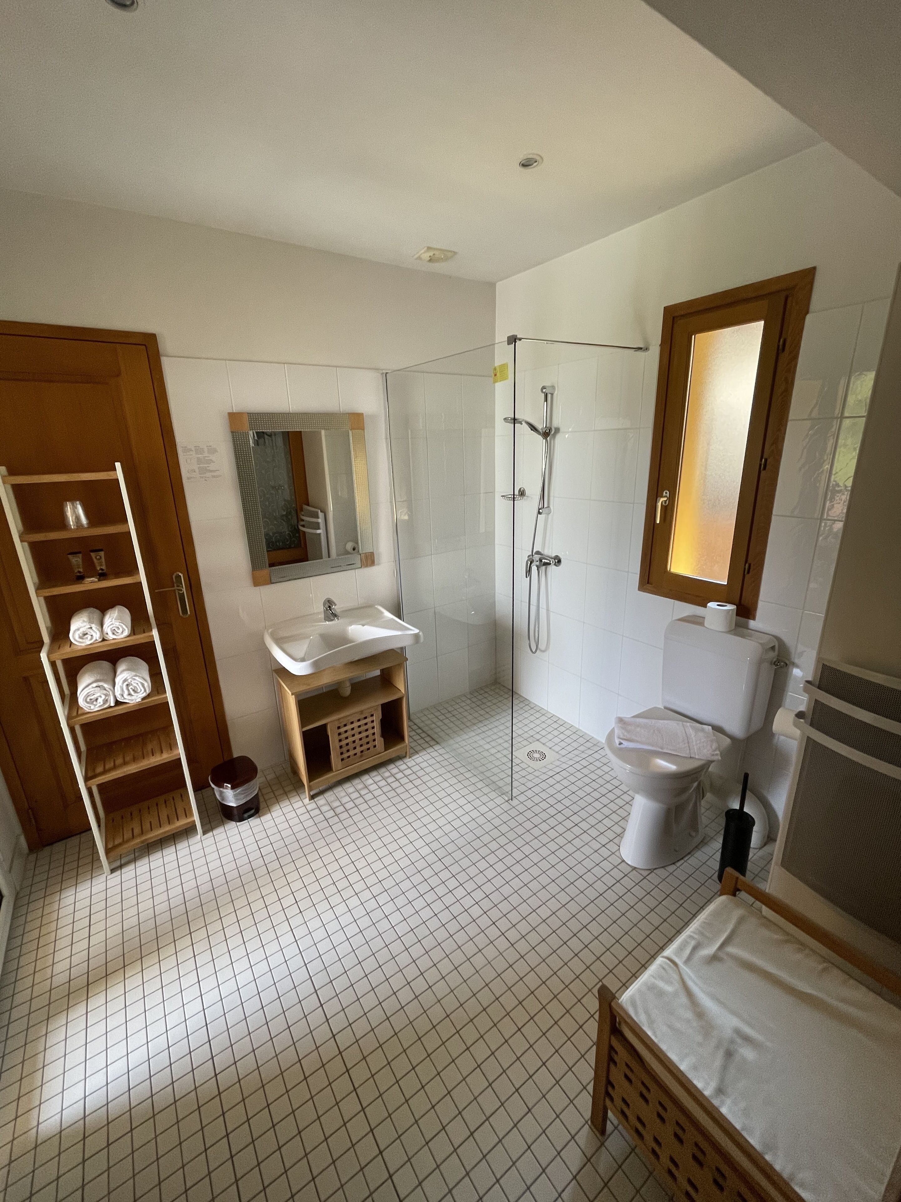 A bathroom with a wooden vanity, a glass shower enclosure, a toilet, and a sink.