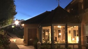A wooden deck leading to a building with a covered patio area, outdoor seating, and a view of the surrounding landscape. - Hôtel de la Vallée Heureuse (Poligny)