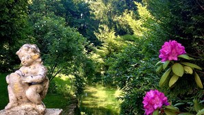 A garden with a statue, a pond, and blooming flowers. - Hôtel de la Vallée Heureuse (Poligny)
