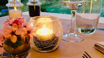 A table set with candles, glasses, and a vase of flowers.