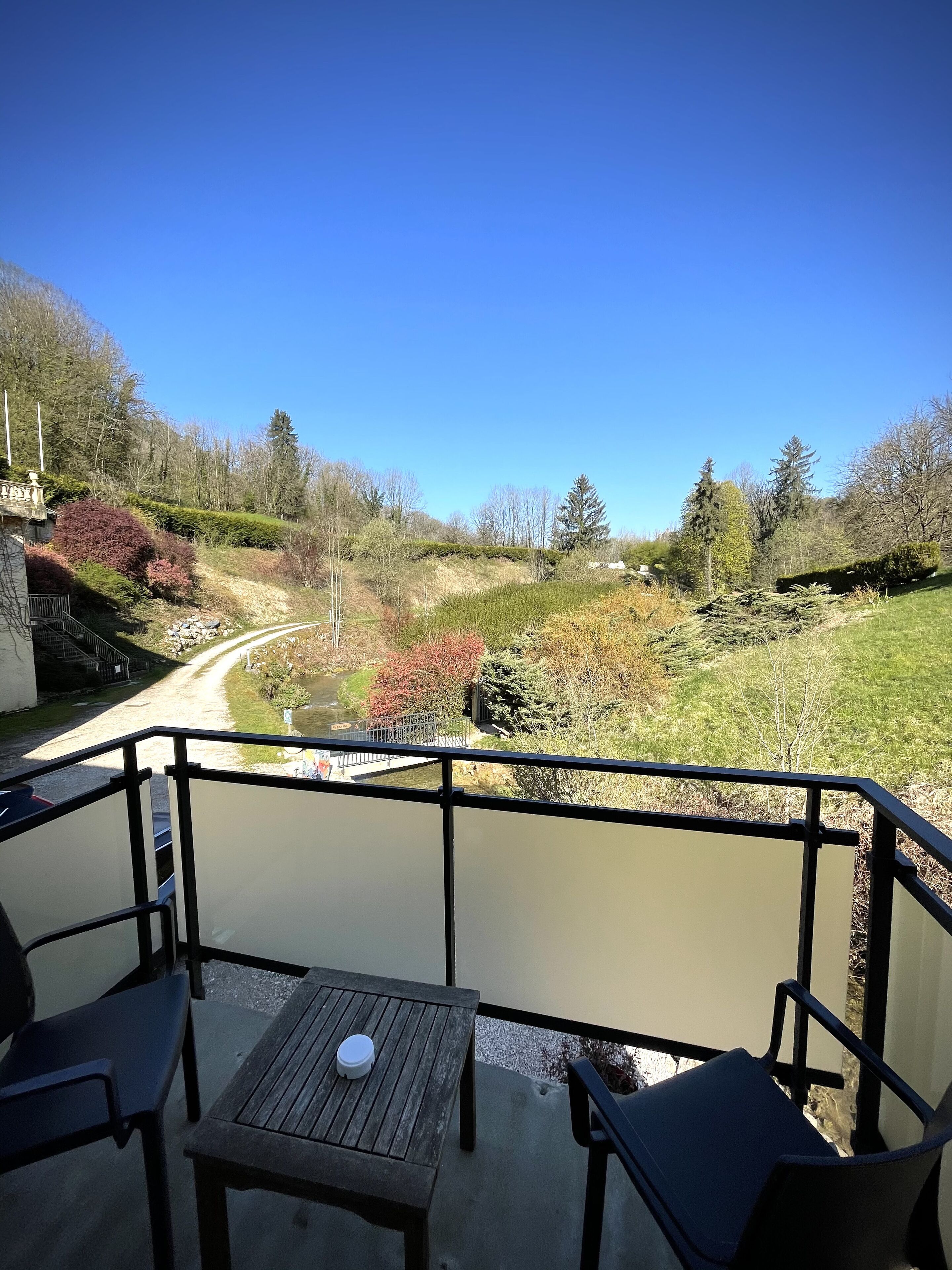 A balcony with a view of a river and surrounding greenery.