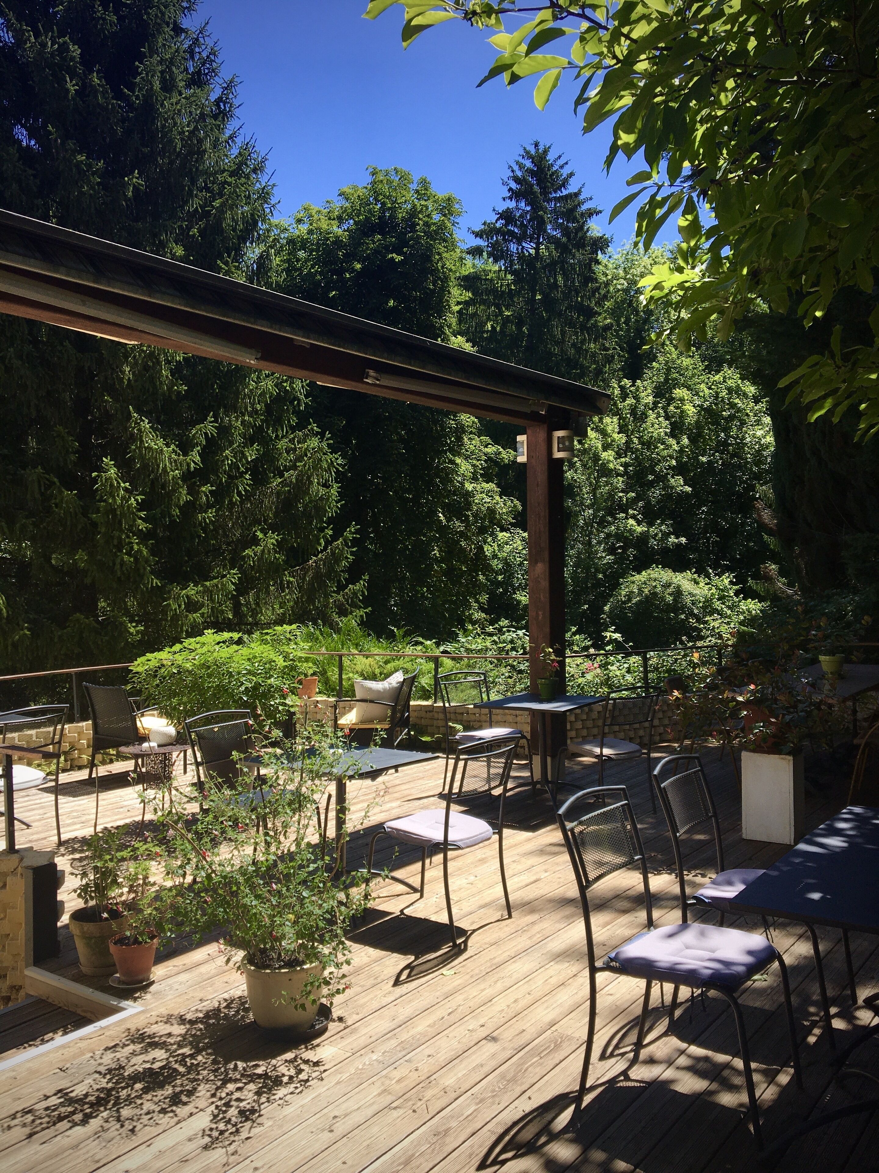 Un patio al aire libre con piso de madera, sillas y mesas de metal.