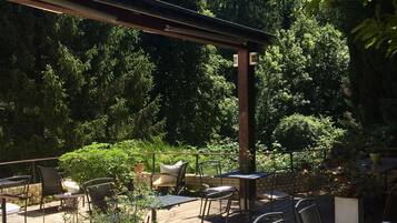 Un patio al aire libre con piso de madera, sillas y mesas de metal.