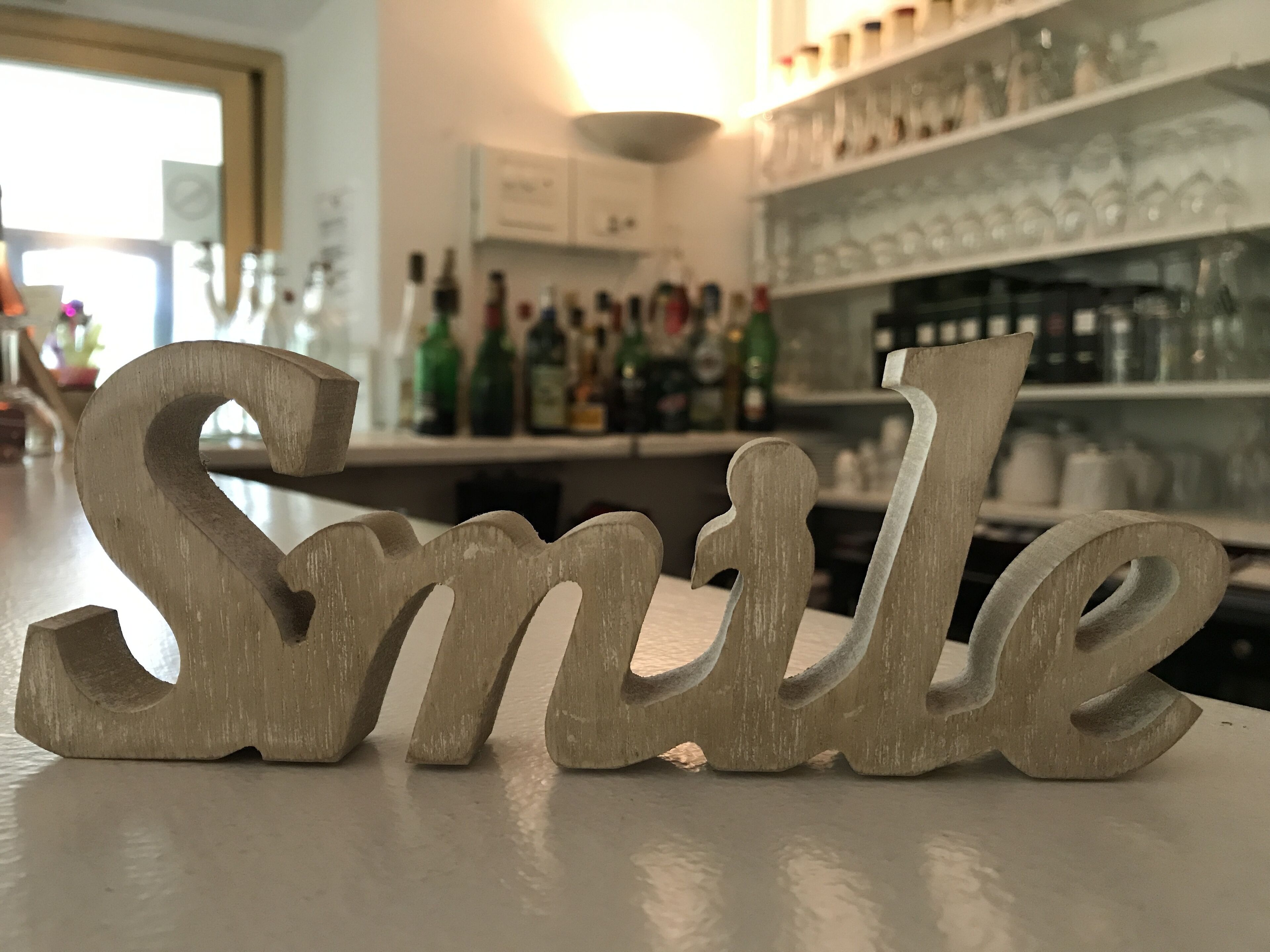Un letrero de madera con la palabra 'Smile' en estilo rústico.