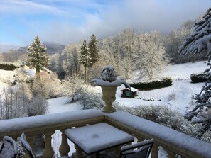 A snow-covered garden with a wooden bench and table, a stone fountain, and a wooden cabin in the background. - Hôtel de la Vallée Heureuse (Poligny)