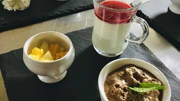 Una mesa de postres con diferentes opciones, incluyendo un vaso de bebida en capas, un bol de fruta y un postre de chocolate.