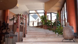 A marble staircase with a rope barrier, potted plants, and a large ceramic pot. - Ares Hotel (San Giovanni la Punta)