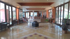 A spacious lobby with large windows, a central seating area, and a reception desk.