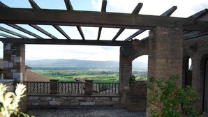 Una construcció de pedra amb una pèrgola de fusta, que ofereix vistes a un paisatge rural.