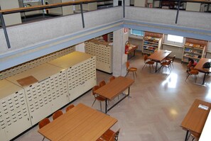 Study in comfort with tables and chairs for group or individual work, surrounded by shelving units and ample storage.