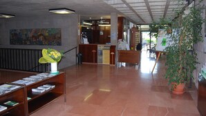 Un vestíbul ampli amb una taquilla d'informació, una escala i un mural a la paret.