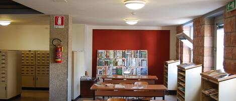 A library with wooden desks, bookshelves, and a fire extinguisher.