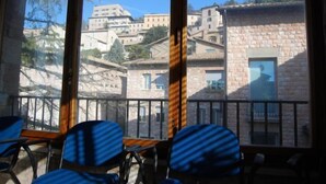 Habitació amb vista a una vila situada en un turó, amb edificis de pedra i un balcó amb cadires.