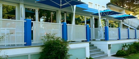 A building with a covered outdoor area, steps leading up to it, and a white fence.