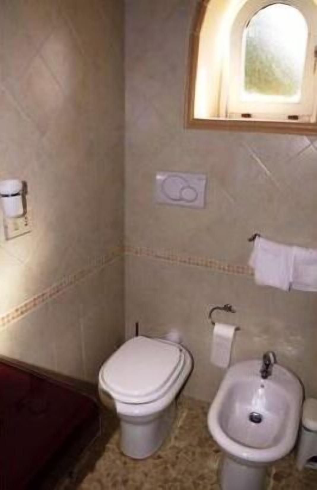 Un baño con inodoro, bidé y una pequeña ventana.