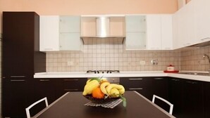 A kitchen with dark cabinets, a white countertop, and a fruit bowl on the table. - B&B Raggio di Sole (Trevignano Romano)