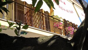 A building with a balcony, a sign with text, and potted plants. - B&B Raggio di Sole (Trevignano Romano)