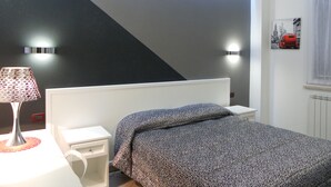 A bedroom with a bed, bedside table, lamp, and wall-mounted light fixtures. - B&B Raggio di Sole (Trevignano Romano)