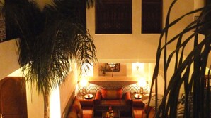 A cozy lounge area with a sofa set, a coffee table, and a decorative wall with a geometric window pattern.