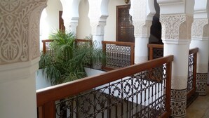 An interior courtyard with arches, a wooden railing, and decorative columns.