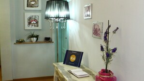 Una mesa de recepción con un letrero, una planta en maceta y un florero con flores.