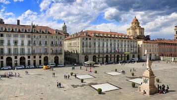 A spacious public square with historic buildings, a clock tower, and a statue.