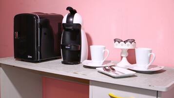 Une petite cuisine équipée d’une machine à café, de deux tasses et d’une assiette avec une cuillère.